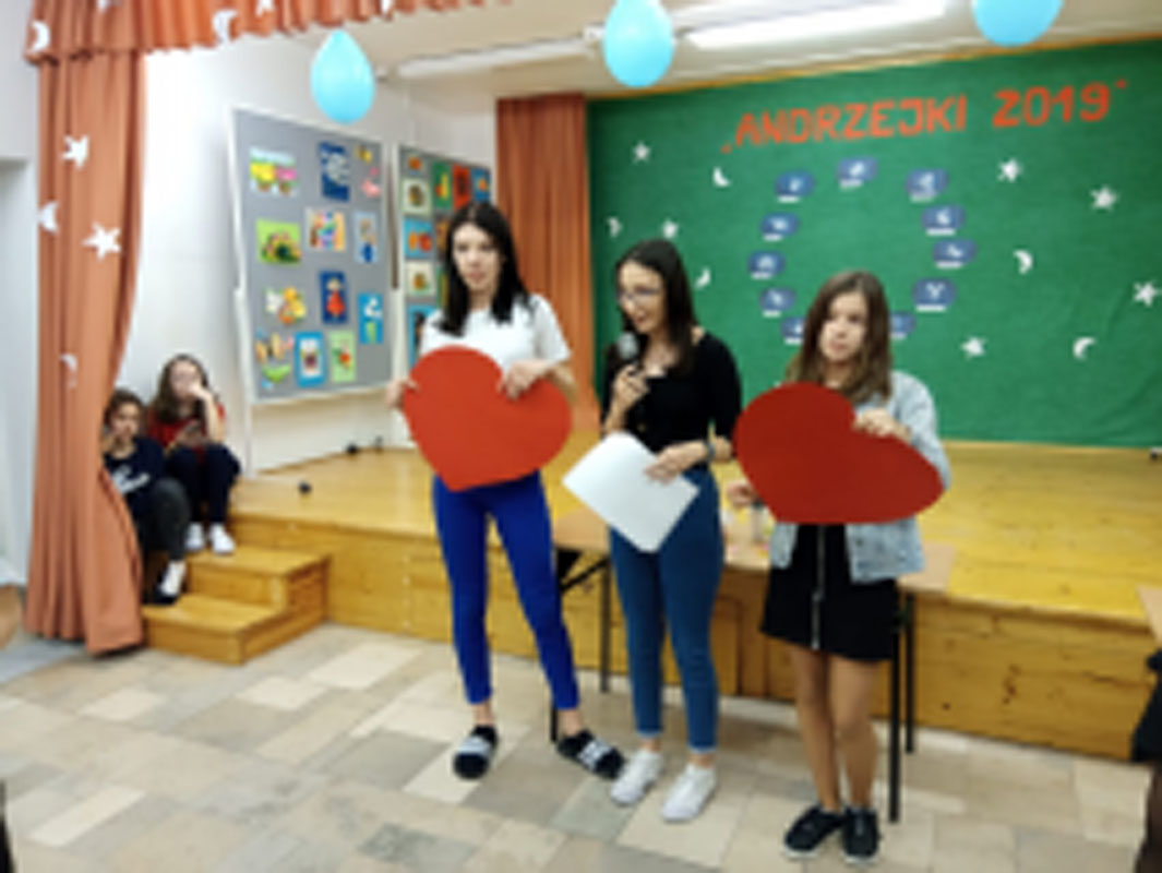 Uczniowie biorą udział w zabawach andrzejkowych, układają buty jeden za drugim, tańczą.