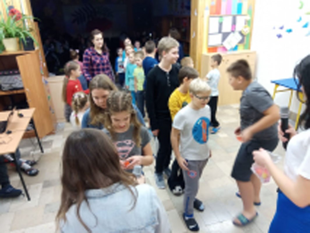 Uczniowie biorą udział w zabawach andrzejkowych, układają buty jeden za drugim, tańczą.