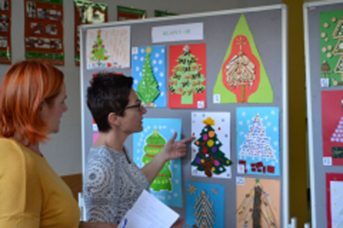 Galeria zawiera 8 zdjęć tablic z pracami plastycznymi. Przy dwóch nauczycielki oglądają prace.