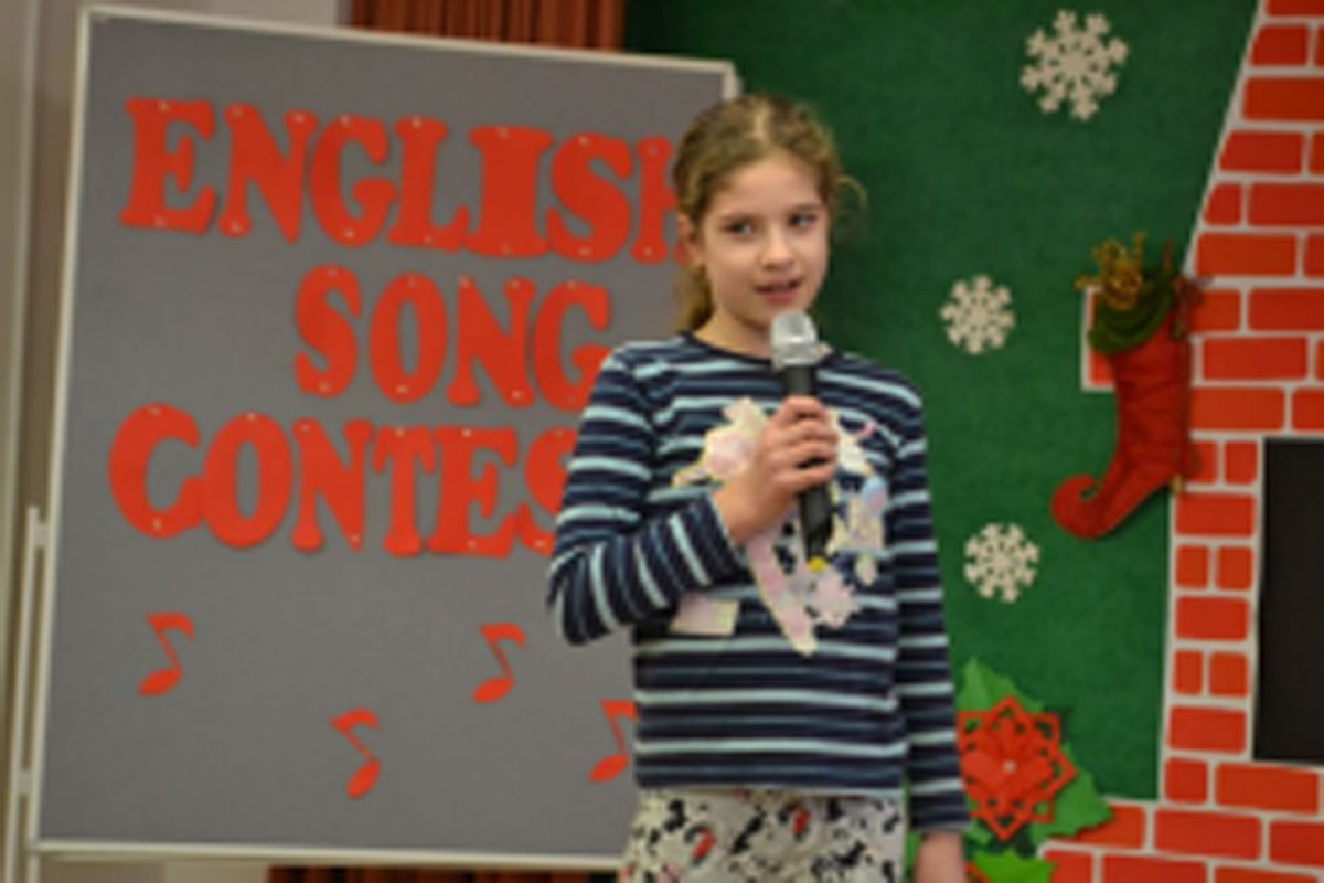 Uczniowie występują na scenie, trzymają mikrofony. Członkowie jury siedzą przy stoliku, wręczają dyplomy. Wspólne zdjęcie uczniów.