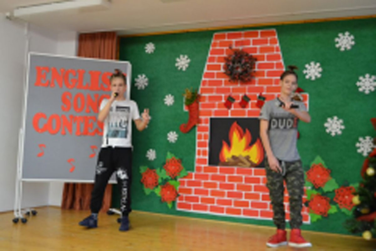 Uczniowie występują na scenie, trzymają mikrofony. Członkowie jury siedzą przy stoliku, wręczają dyplomy. Wspólne zdjęcie uczniów.