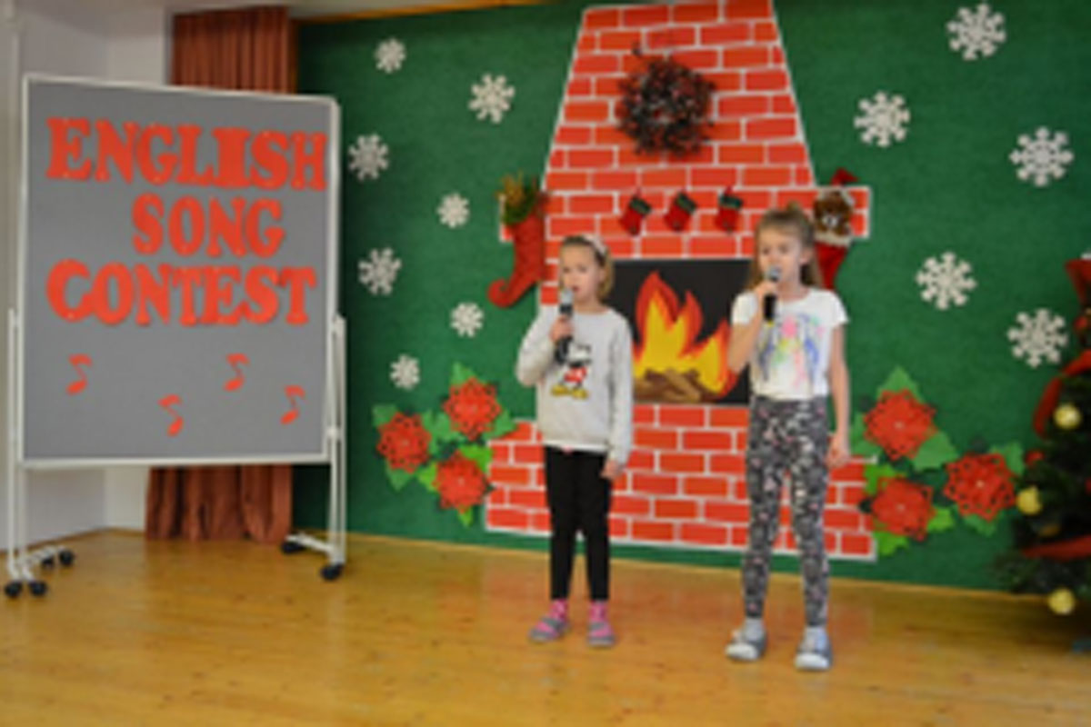 Uczniowie występują na scenie, trzymają mikrofony. Członkowie jury siedzą przy stoliku, wręczają dyplomy. Wspólne zdjęcie uczniów.