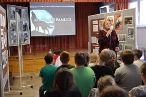 Zdjęcia przedstawiają salę, w której siedzą  uczniowie szkoły i oglądają prezentację.  Z frontu wystawione są stelaże, na których przypięte są zdjęcia przedstawiające Żołnierzy Wyklętych. Na jednym ze zdjęć przedstawiony jest dyrektor szkoły i nauczycielk