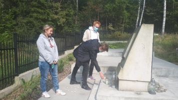 Uczniowie przy nagrobkach zapalają znicze.