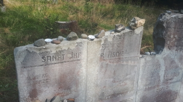 Uczniowie przy nagrobkach zapalają znicze.