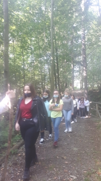 Uczniowie przy nagrobkach zapalają znicze.