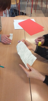 Uczniowie siedzą przy stolikach, rozwiązują rebusy, krzyżówki i wykreślanki, układają puzzle. Na stołach są ołówki, kleje, opakowania po jajkach niespodziankach, kartki w różnych kolorach. Uczniowie wykonują gazetkę z kart z zasadami bezpieczeństwa w siec