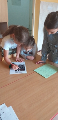 Dziewczynki wykonują działania na karcie pracy.