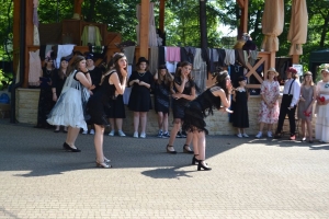 uczniowie przebrani w stroje z lat 20, 30,  tańczą, bawią się w stare gry, śpiewają, przedstawiają, oglądają teatrzyk