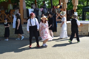 uczniowie przebrani w stroje z lat 20, 30,  tańczą, bawią się w stare gry, śpiewają, przedstawiają, oglądają teatrzyk