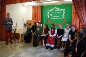 Uczniowie na scenie śpiewają pieśni. Koło sceny poczet sztandarowy, na scenie uczniowie przebrani w czarne stroje zaborców i  na biało za orła. Uczniowie składają znicze pod krzyżem.