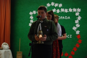 Uczniowie na scenie śpiewają pieśni. Koło sceny poczet sztandarowy, na scenie uczniowie przebrani w czarne stroje zaborców i  na biało za orła. Uczniowie składają znicze pod krzyżem.