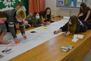 Uczniowie wykonują plakat na papierze wielkoformatowym.