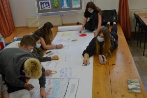 Uczniowie wykonują plakat na papierze wielkoformatowym.