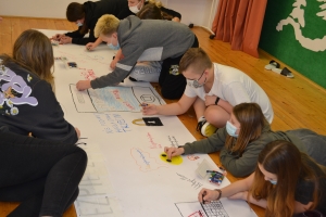 Uczniowie wykonują plakat na papierze wielkoformatowym.