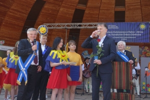 Występujący na scenie tańczą z pomponami, ze wstęgami. Na scenie dekoracja, pacynki Jacek i Agatka. Order Uśmiechu wręcza sekretarz Kapituły Orderu Uśmiechu i państwo Burcanowie.