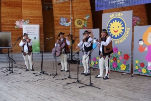 Występujący na scenie tańczą z pomponami, ze wstęgami. Na scenie dekoracja, pacynki Jacek i Agatka. Order Uśmiechu wręcza sekretarz Kapituły Orderu Uśmiechu i państwo Burcanowie.