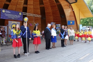 Występujący na scenie tańczą z pomponami, ze wstęgami. Na scenie dekoracja, pacynki Jacek i Agatka. Order Uśmiechu wręcza sekretarz Kapituły Orderu Uśmiechu i państwo Burcanowie.