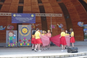 Występujący na scenie tańczą z pomponami, ze wstęgami. Na scenie dekoracja, pacynki Jacek i Agatka. Order Uśmiechu wręcza sekretarz Kapituły Orderu Uśmiechu i państwo Burcanowie.